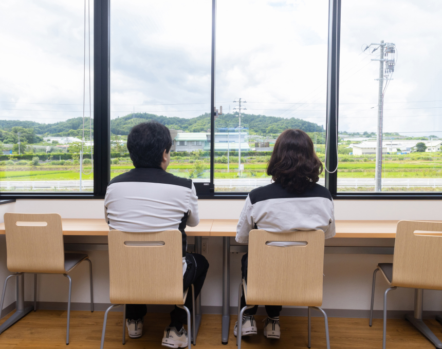 カフェテリアから外の自然豊かな景色を眺める2人の社員