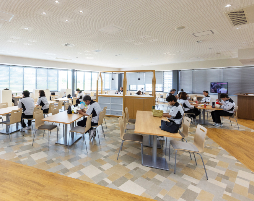 広々とした明るいカフェテリア（社員食堂）で食事や休憩をとる大勢の社員たち