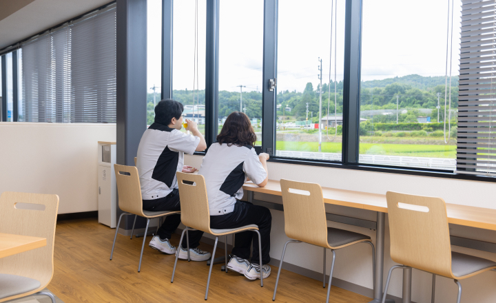 窓際のカウンター席で外の景色を眺めながら休憩する社員たち