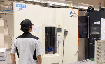 多数の工作機械が並ぶ、白を基調とした清潔で明るい工場内の風景