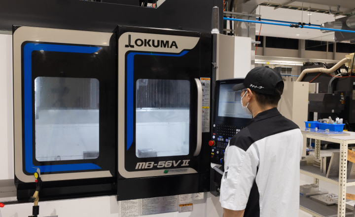 工作機械の制御パネルを操作し、日々の業務に取り組む社員